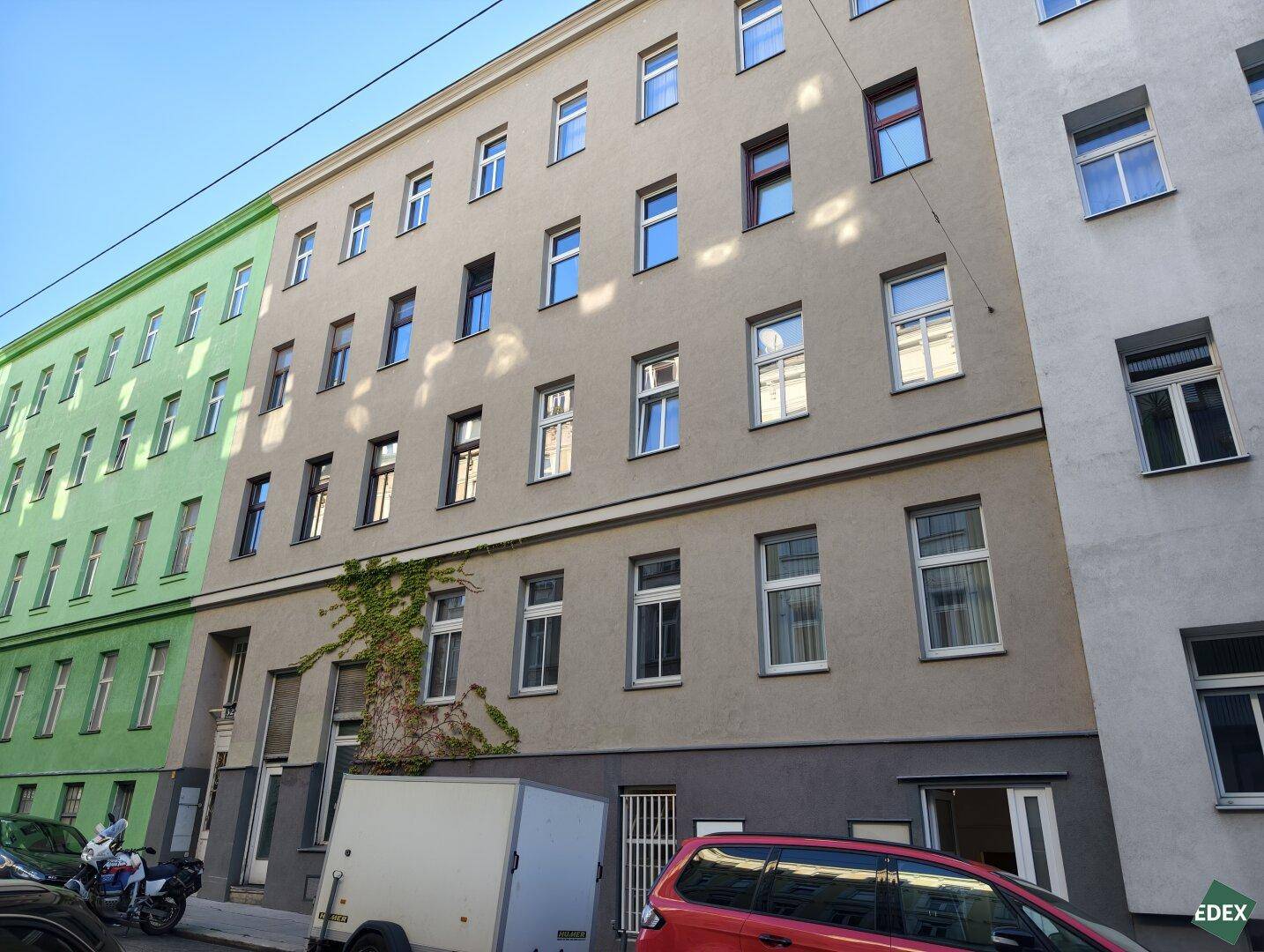Mehrstöckiges Wohngebäude mit zahlreichen Fenstern und einer schlichten Fassade an einer Straße.