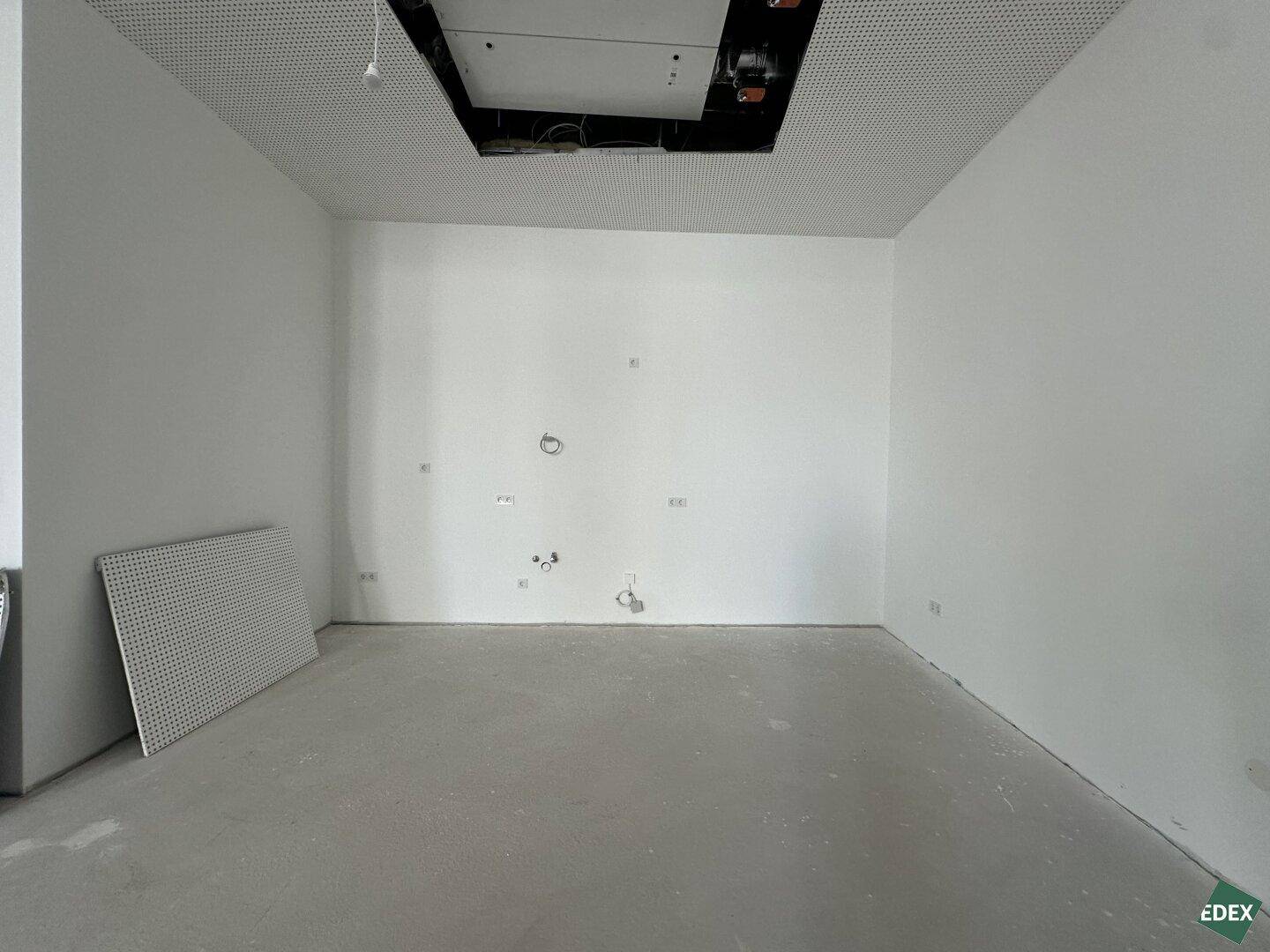 Kleinerer, leerer Raum innerhalb des Gewerbebereichs mit Betonboden, weißen Wänden und perforierter Decke.