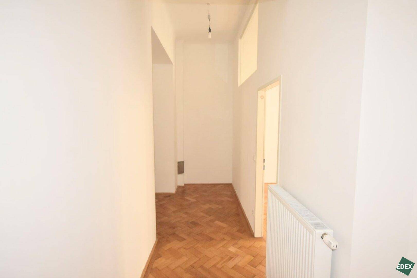 Langer, heller Flur mit klassischem Fischgrätparkett, der verschiedene Räume der Wohnung verbindet.