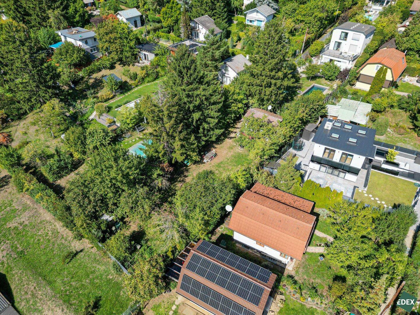 Weitläufige Luftaufnahme der Wohngegend mit vielen Gärten, Häusern und Solaranlagen auf Dächern.