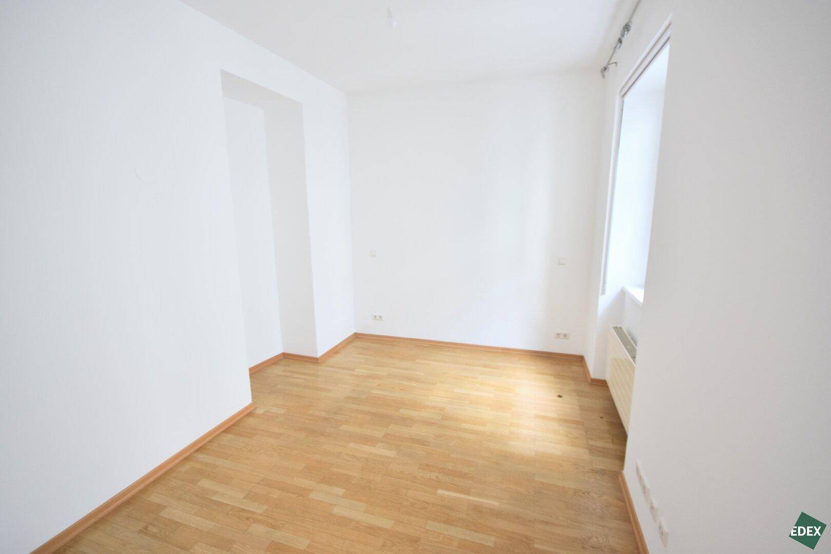 Ruhiges Zimmer mit hellem Parkettboden und Fenster, vielseitig nutzbar als Schlaf- oder Arbeitszimmer.