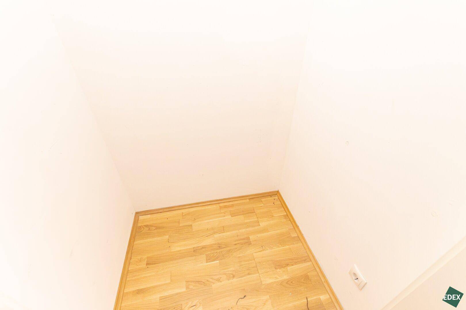 Kleiner, leerer Raum mit Holzboden und weißen Wänden, der als Abstellkammer dienen könnte.