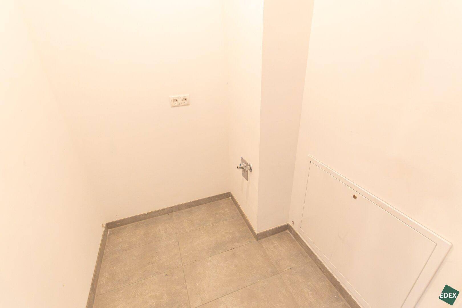 Kleiner Hauswirtschaftsraum mit Fliesenboden und Anschlüssen für Waschmaschine oder Trockner.