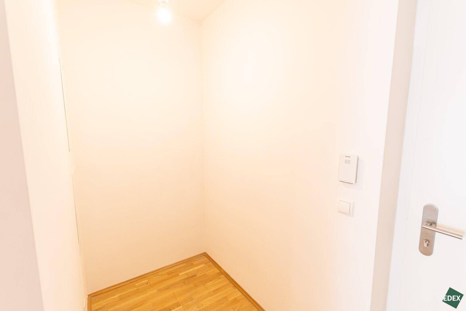 Kleiner, leerer Abstellraum mit Holzboden und weißen Wänden, ideal für zusätzlichen Stauraum.