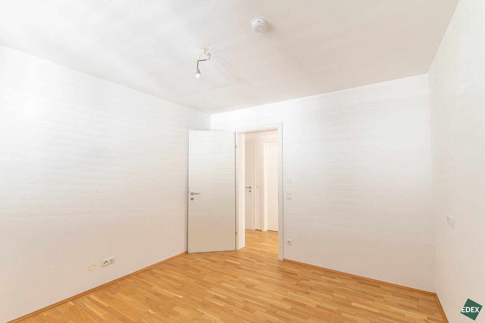 Geräumiges Zimmer mit Parkettboden und weiß gestrichenen Wänden, bereit zur individuellen Gestaltung.