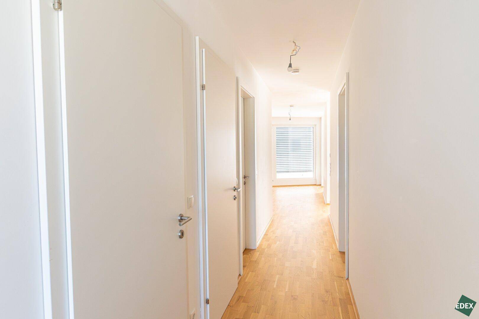 Heller Flur mit Parkettboden, der zu verschiedenen Zimmern der Wohnung führt.