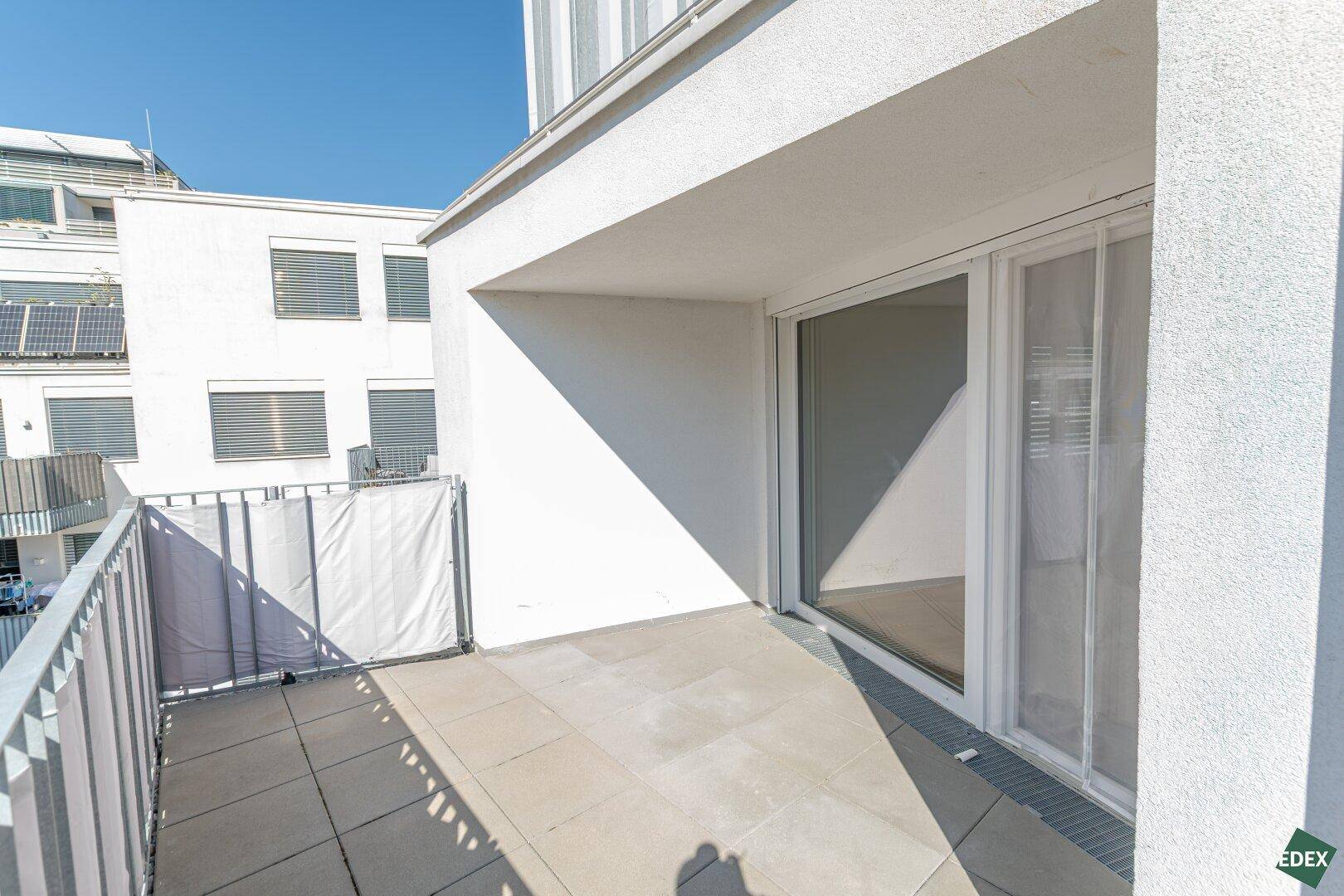 Gemütlicher Balkon mit Fliesenboden und seitlichem Sichtschutz, ideal für entspannte Stunden.