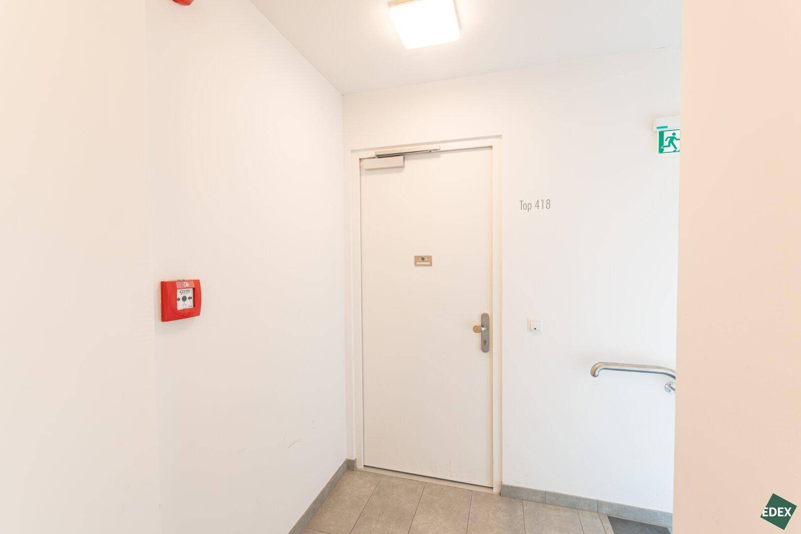Eingangsbereich eines Mehrfamilienhauses mit Wohnungstür und Brandschutzvorrichtungen.