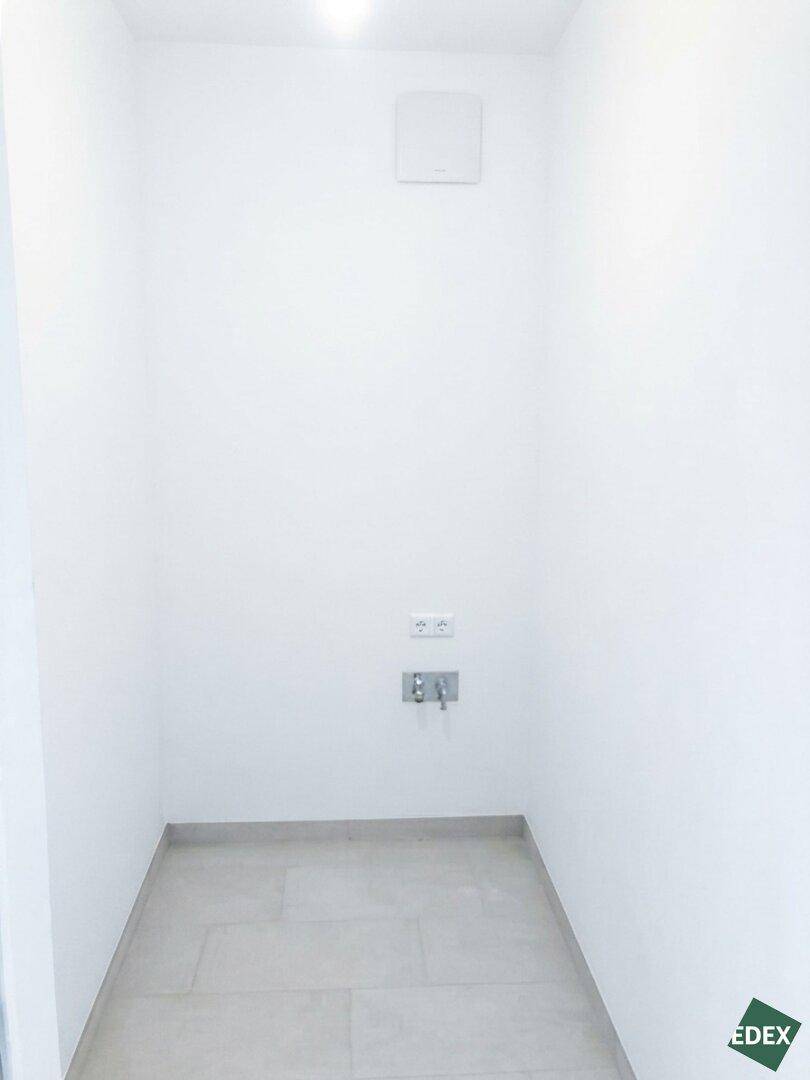 Praktischer Hauswirtschaftsraum mit Fliesenboden und Anschlüssen für Waschmaschine und Trockner.