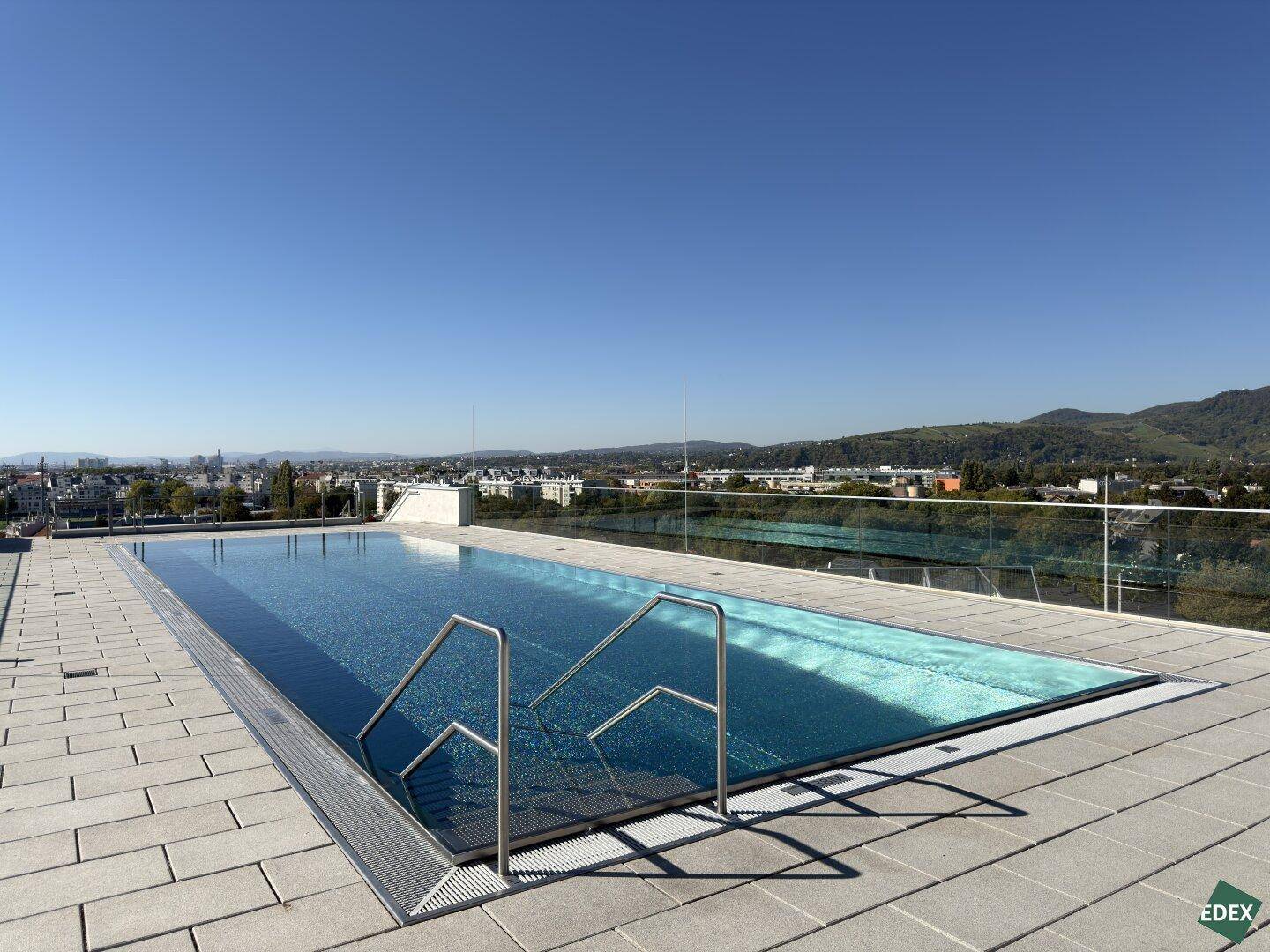 Exklusiver Dachpool mit Panoramablick über die Stadt an einem sonnigen Tag.