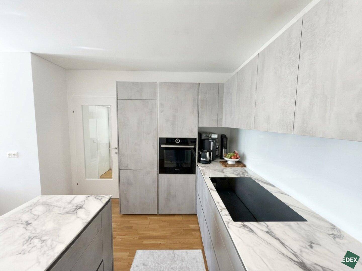 Hochwertige Einbauküche mit integrierten Geräten und stilvollen grauen Fronten, ideal für modernes Wohnen.