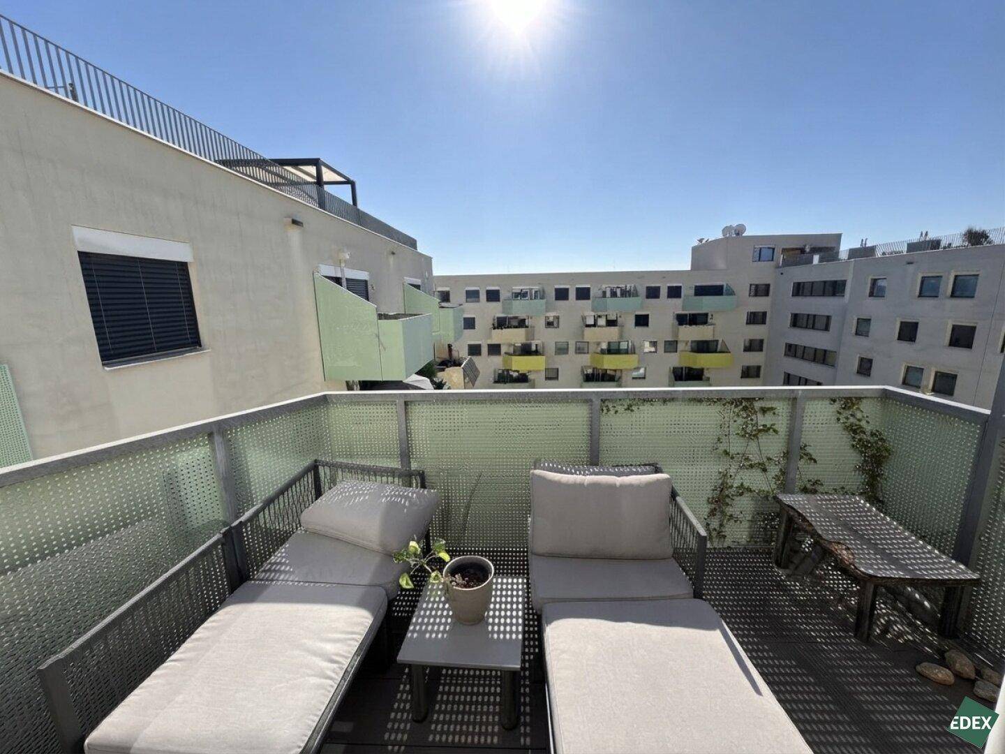 Sonniger Balkon mit Liegestühlen und Blick auf die umliegenden Gebäude, ideal zum Entspannen.
