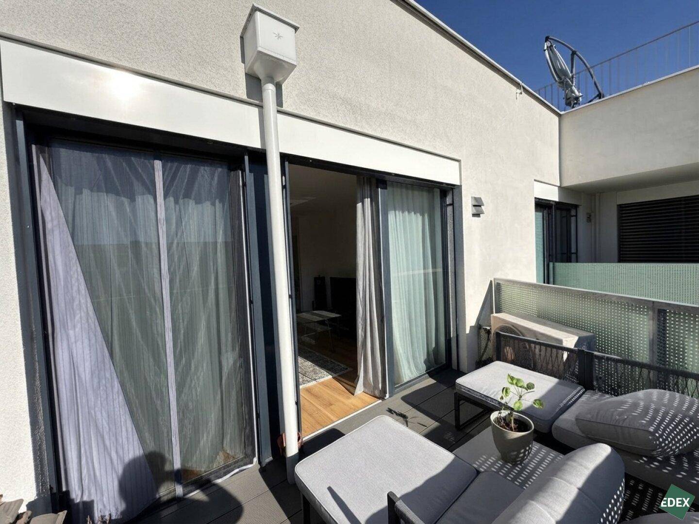 Zugang vom Wohnbereich zur sonnigen Terrasse mit Schiebetüren und Blick auf die Umgebung.