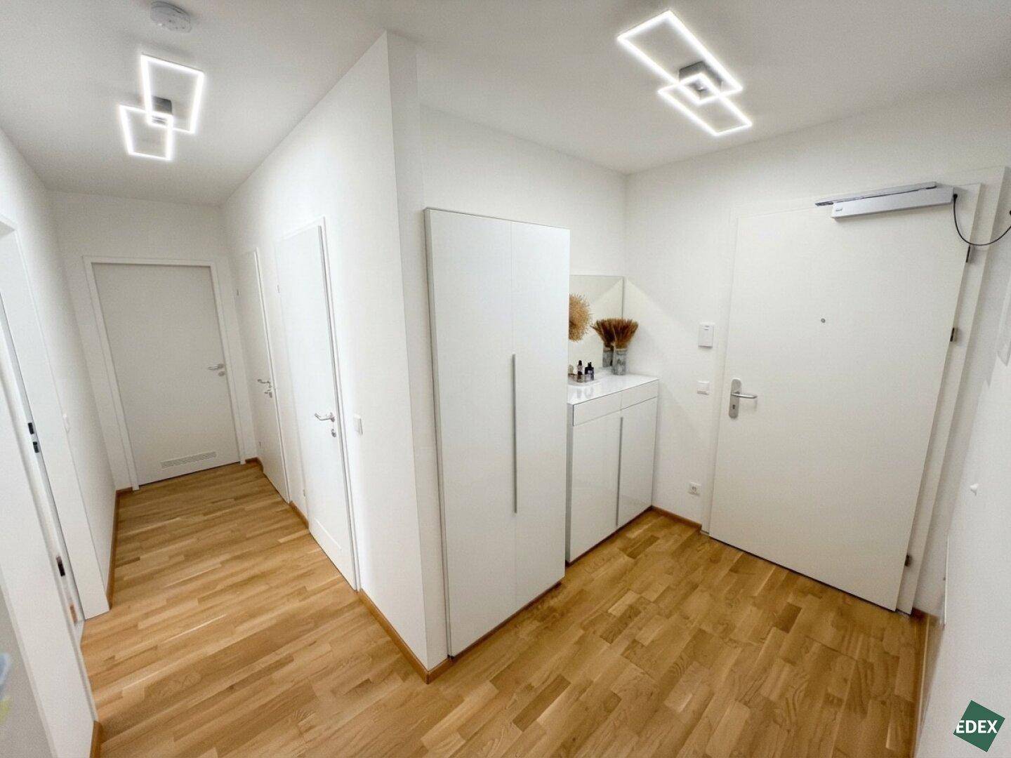 Geräumiger Eingangsbereich mit praktischen weißen Einbauschränken und hellem Holzboden.