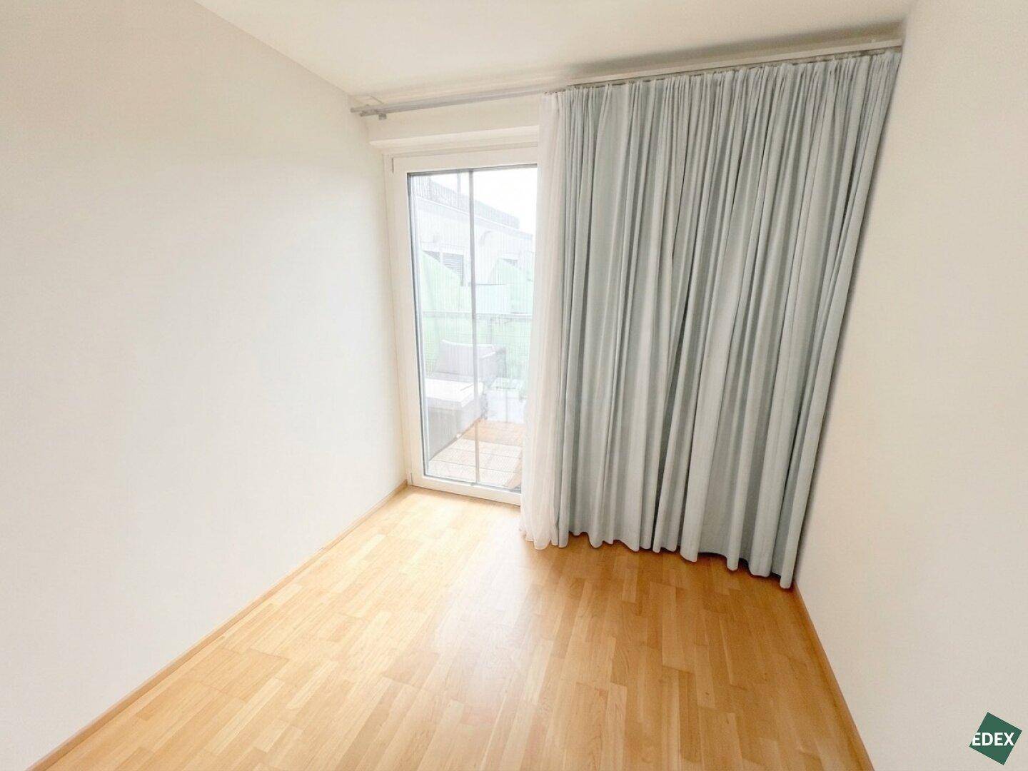 Schlafzimmer mit Holzboden und Zugang zu einem Außenbereich, ideal für frische Luft.