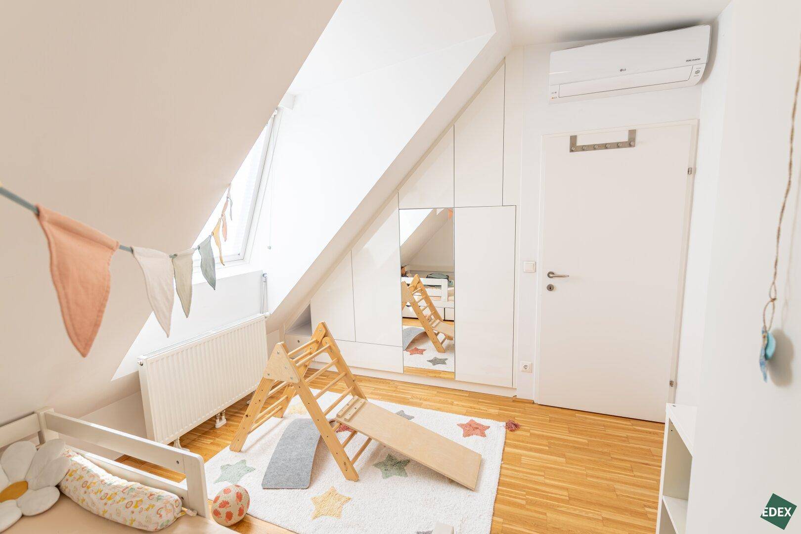 Helles Kinderzimmer mit Einbauschränken, Spielgeräten und Klimaanlage.