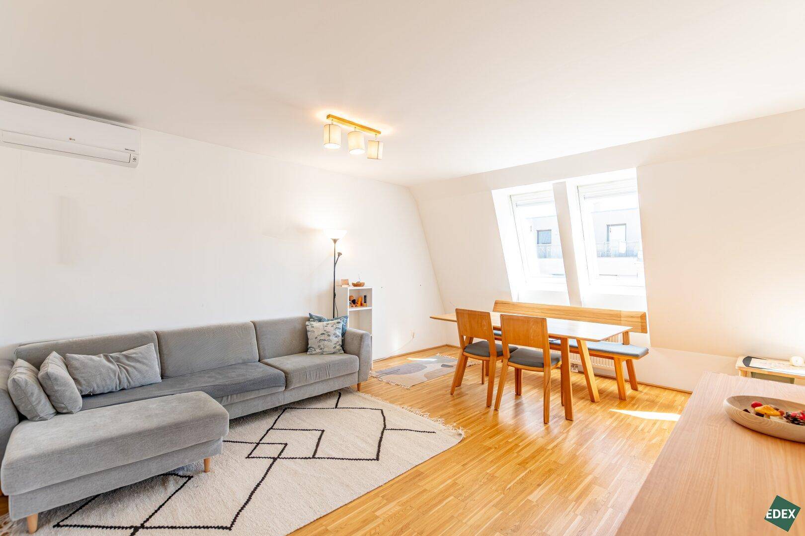 Heller Wohn- und Essbereich mit Sofa, Esstisch und Dachfenstern.