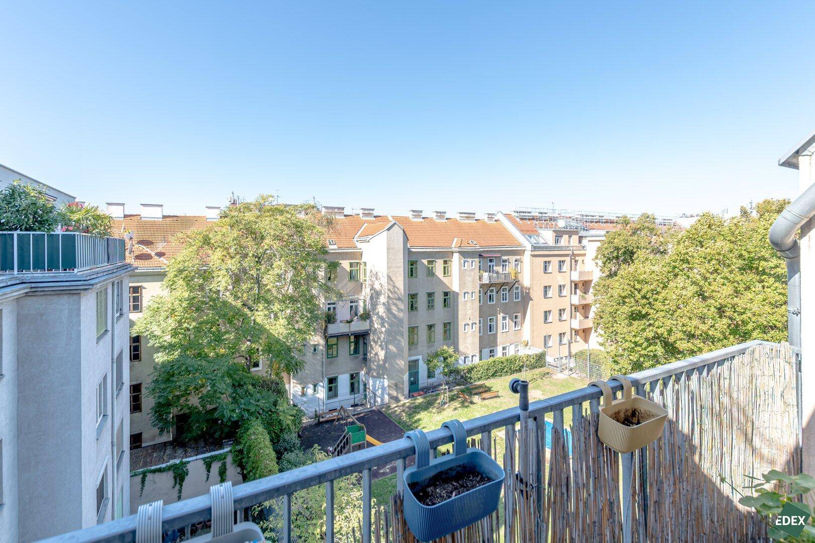 Weitläufiger Blick vom Balkon auf begrünte Innenhöfe und städtische Gebäude.