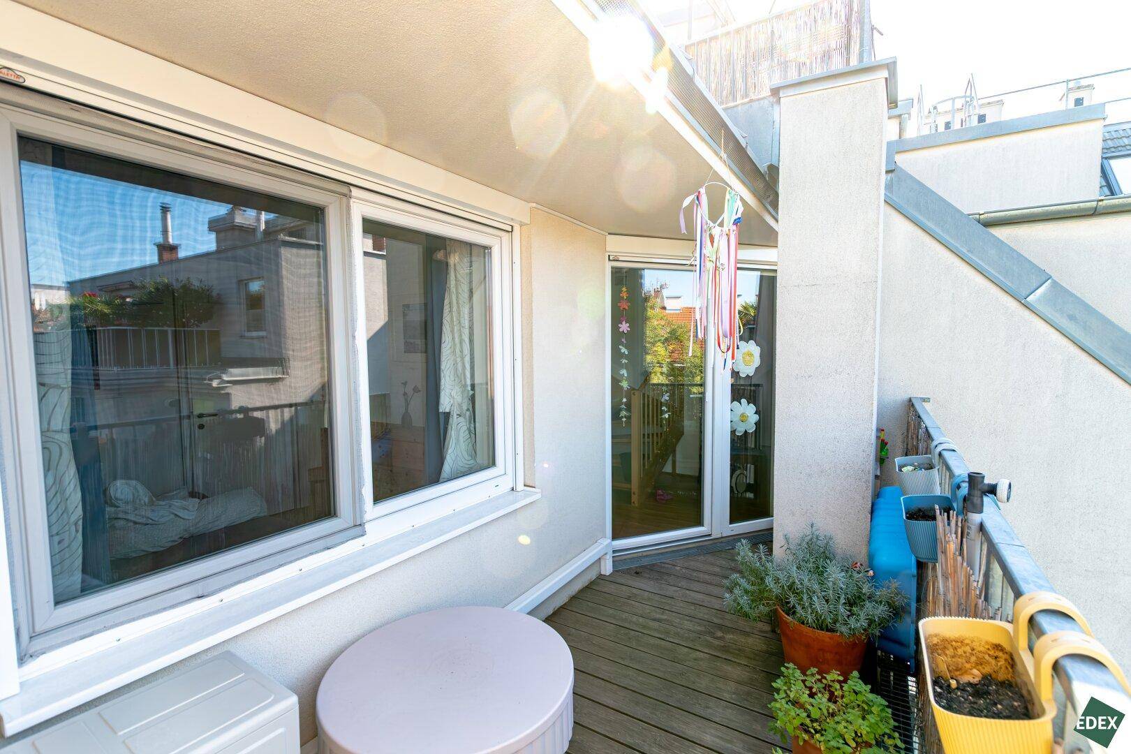 Sonniger Balkon mit Pflanzen und Blick auf die umliegenden Dächer und Gebäude.