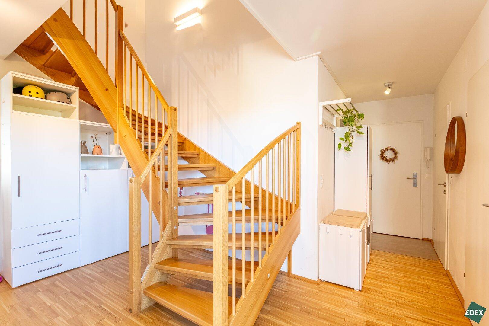 Heller Eingangsbereich mit Holztreppe, Garderobe und Stauraum.