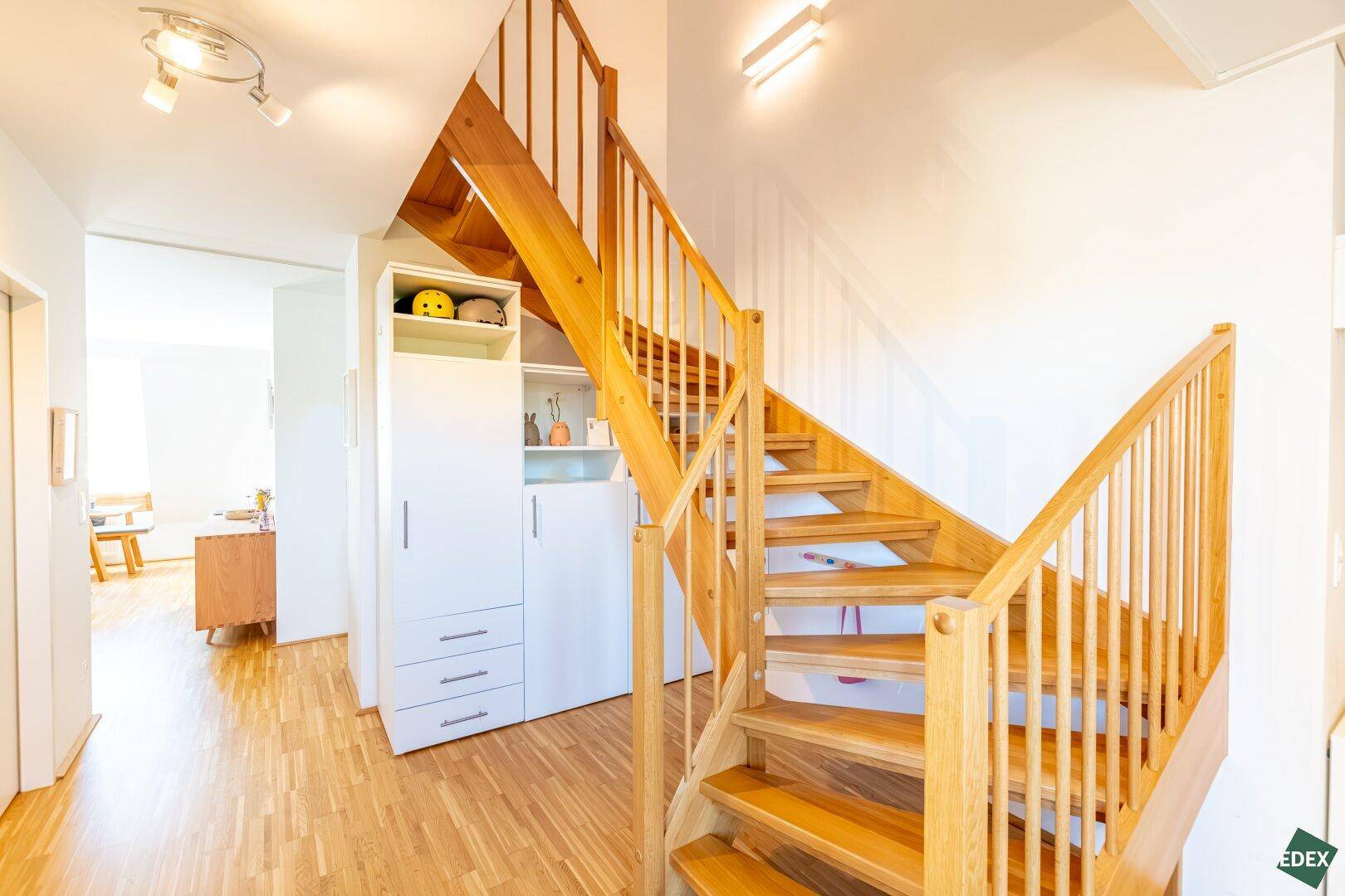 Helle Holztreppe im Eingangsbereich mit integriertem Stauraum unter der Treppe.