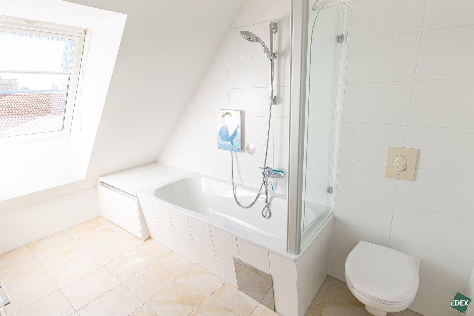 Helles Badezimmer mit Badewanne, WC und Dachfenster für Tageslicht.