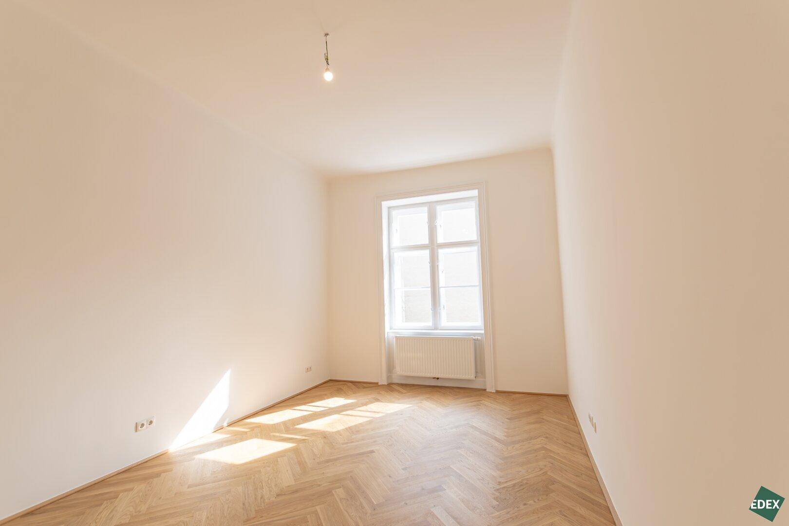 Gemütliches Zimmer mit Fischgrätparkett und einem Fenster, ideal als Schlaf- oder Arbeitszimmer.