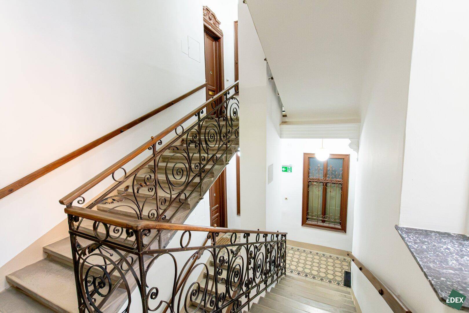 Elegantes Treppenhaus mit schmiedeeisernem Geländer und Marmorstufen in einem Altbau.