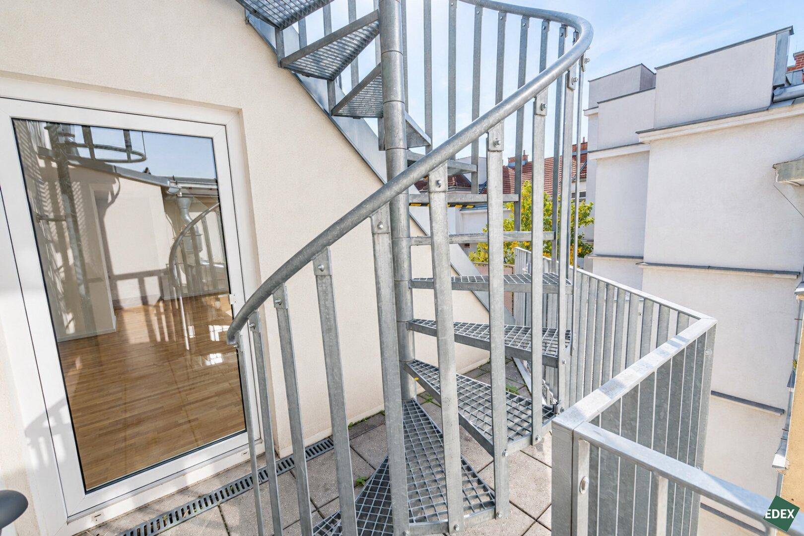 Metall-Wendeltreppe führt von einer Terrasse zu einer weiteren Dachterrasse mit Stadtblick.