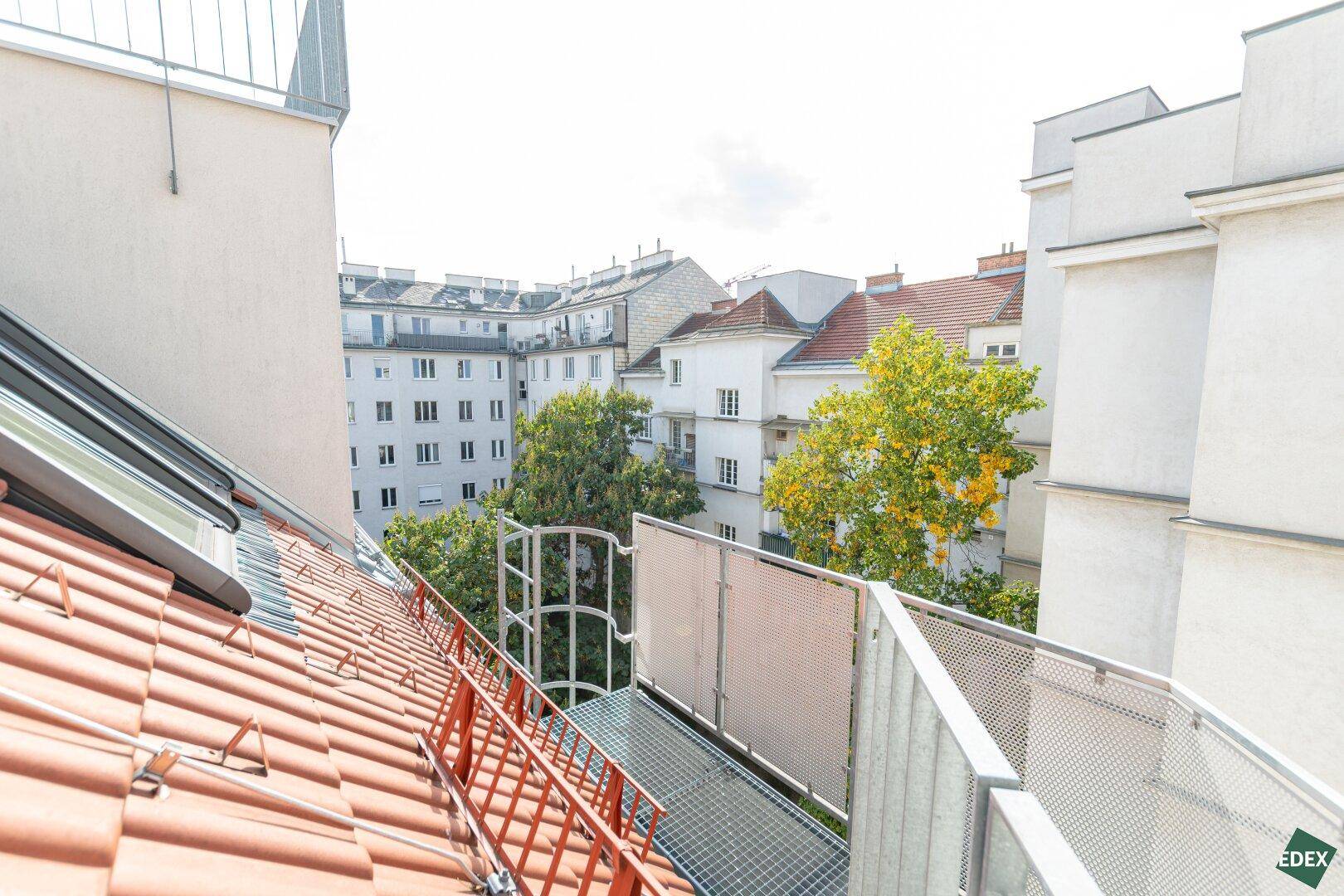 Blick über die Dächer der Stadt mit roten Ziegeln und grünen Bäumen.