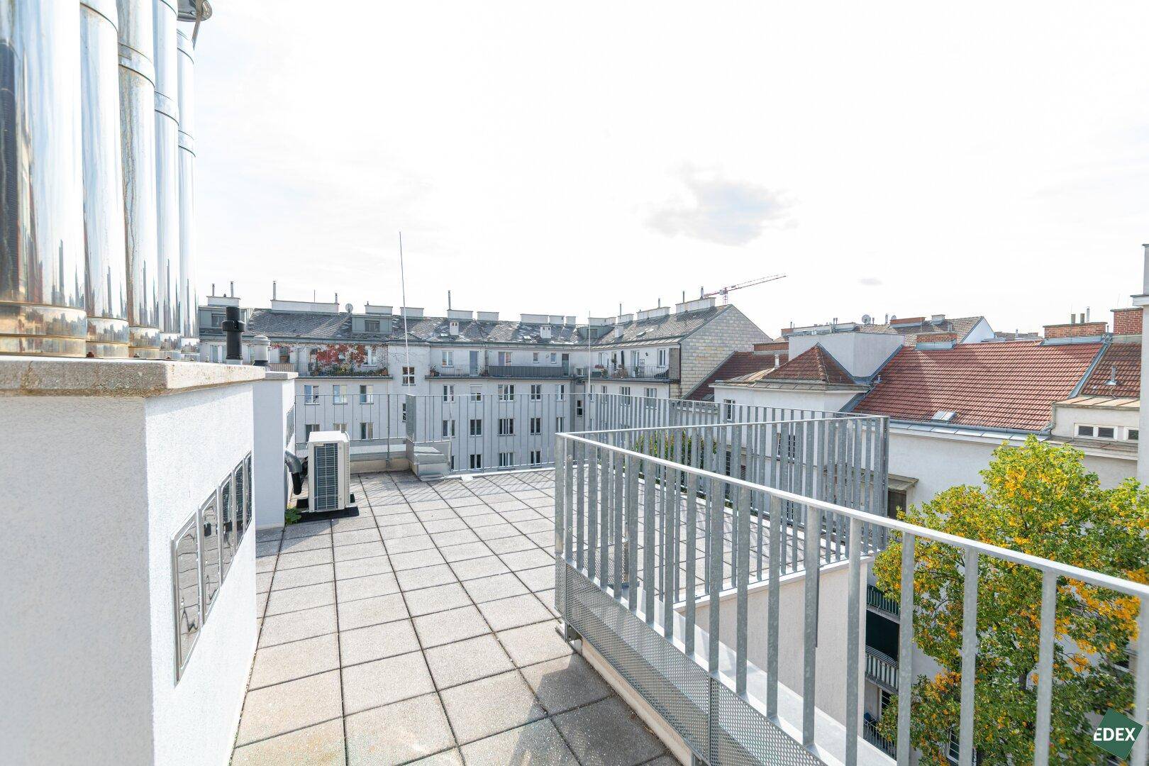 Große Dachterrasse mit weitem Blick über die Stadt und umliegende Gebäude.