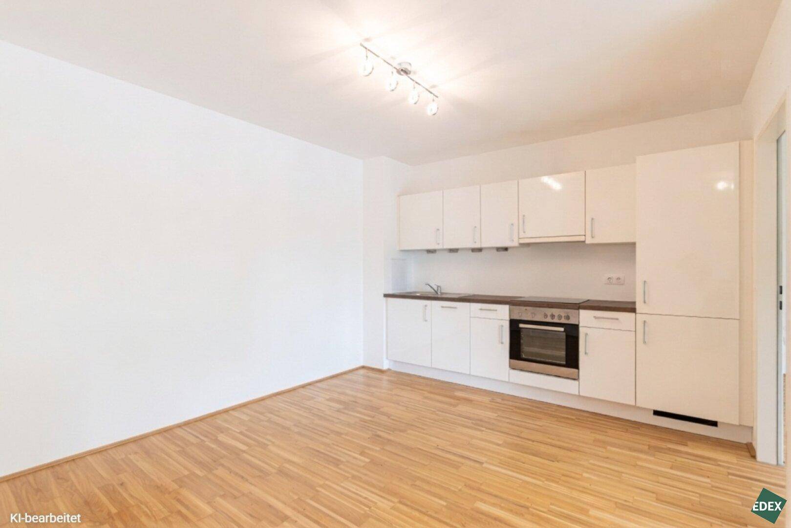 Moderne Küchenzeile mit weißen Hochglanzfronten und integriertem Backofen in hellem Raum.