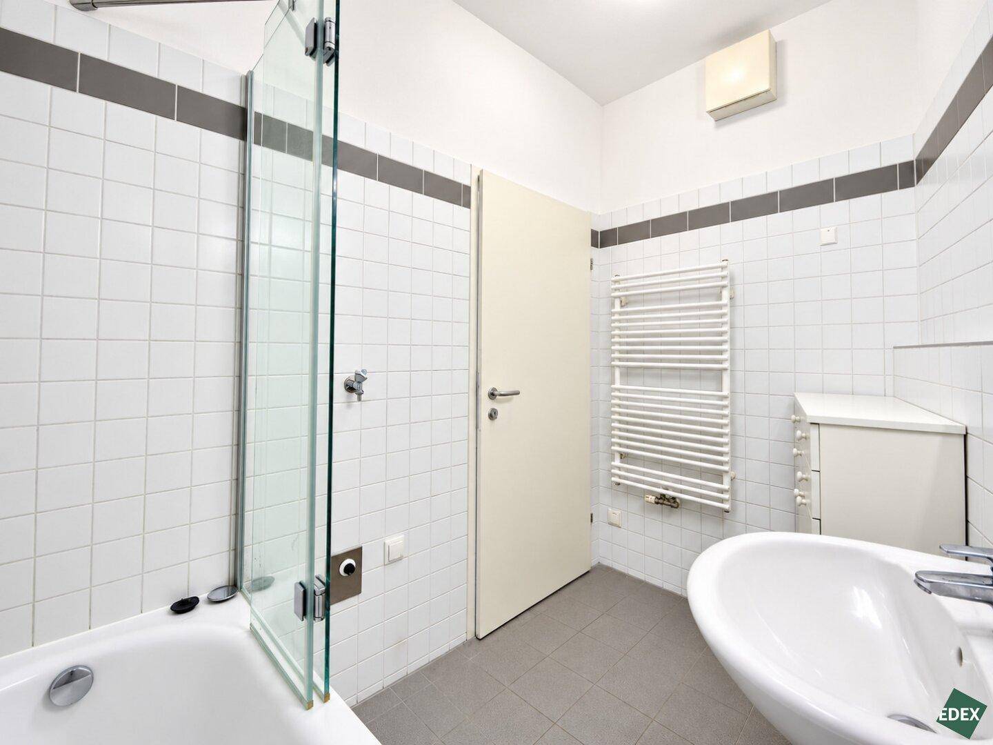 Funktionales Badezimmer mit Badewanne, beheiztem Handtuchhalter und Abluftsystem.