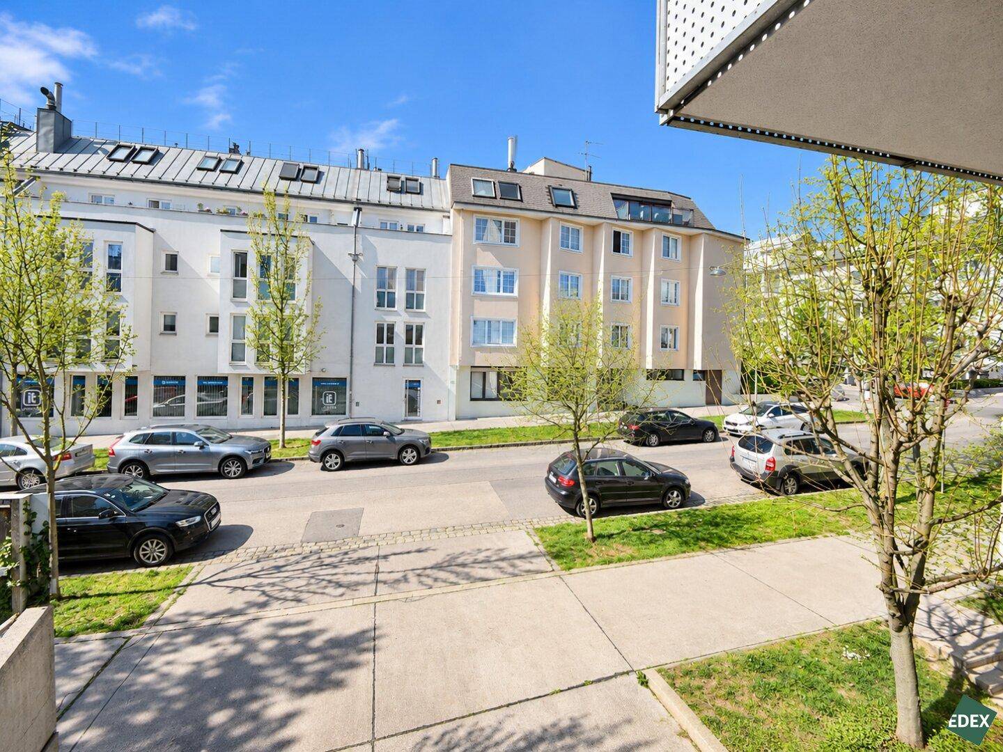 Blick von oben auf eine ruhige Wohnstraße mit parkenden Autos und umliegenden Gebäuden.