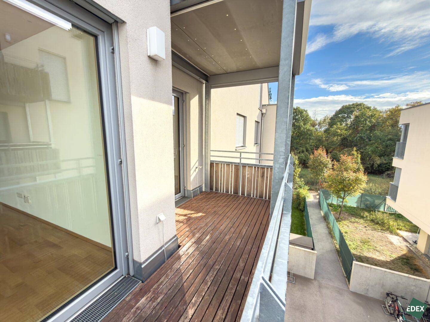 Balkon mit Holzbelag und Blick auf den Gartenbereich sowie die umliegende Natur.