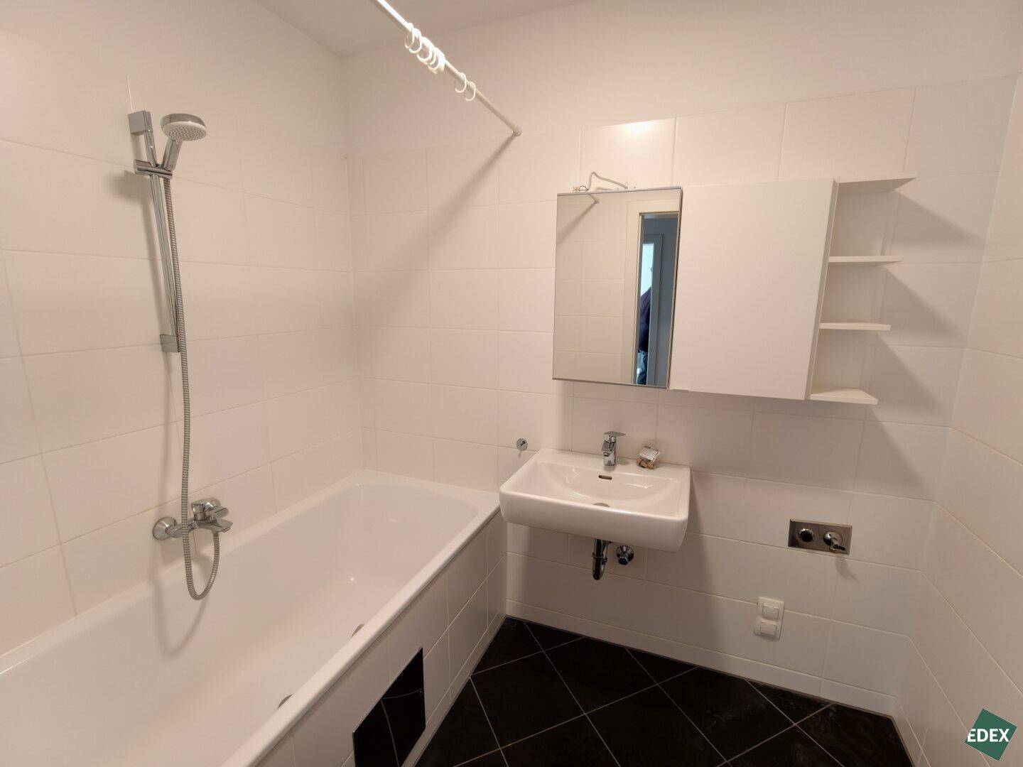 Modernes Badezimmer mit Badewanne, Duschfunktion, Waschbecken und Spiegelschrank.