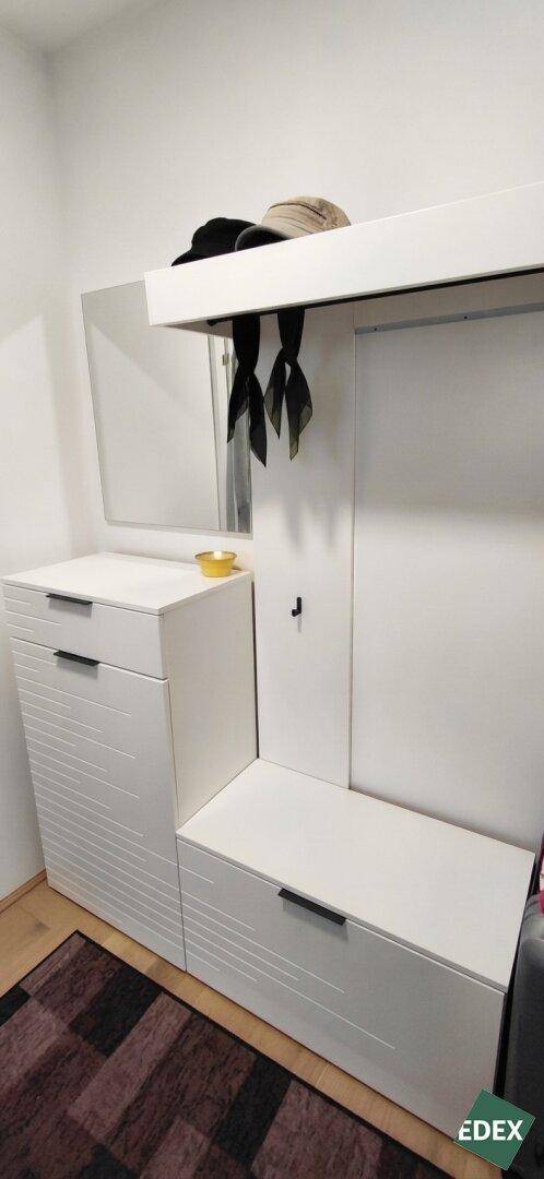 Heller Flur mit Garderobe, Spiegel und Stauraum in Weiß.