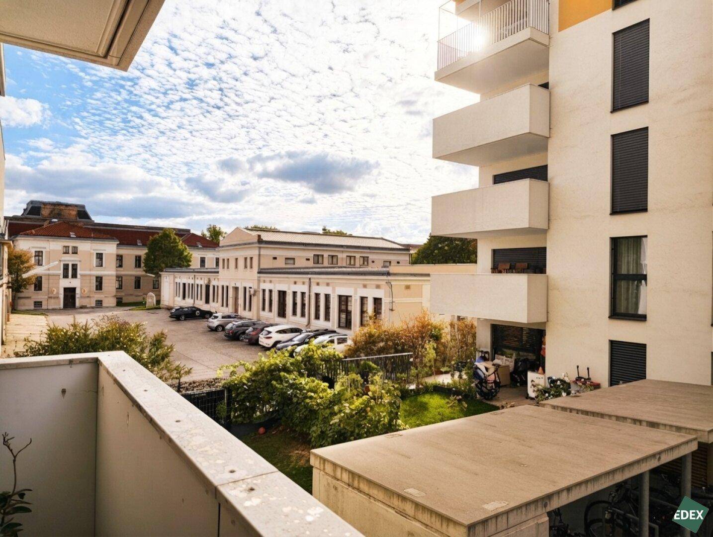 Ausblick vom Balkon auf den Parkplatz und die umliegenden Gebäude der Wohnanlage.