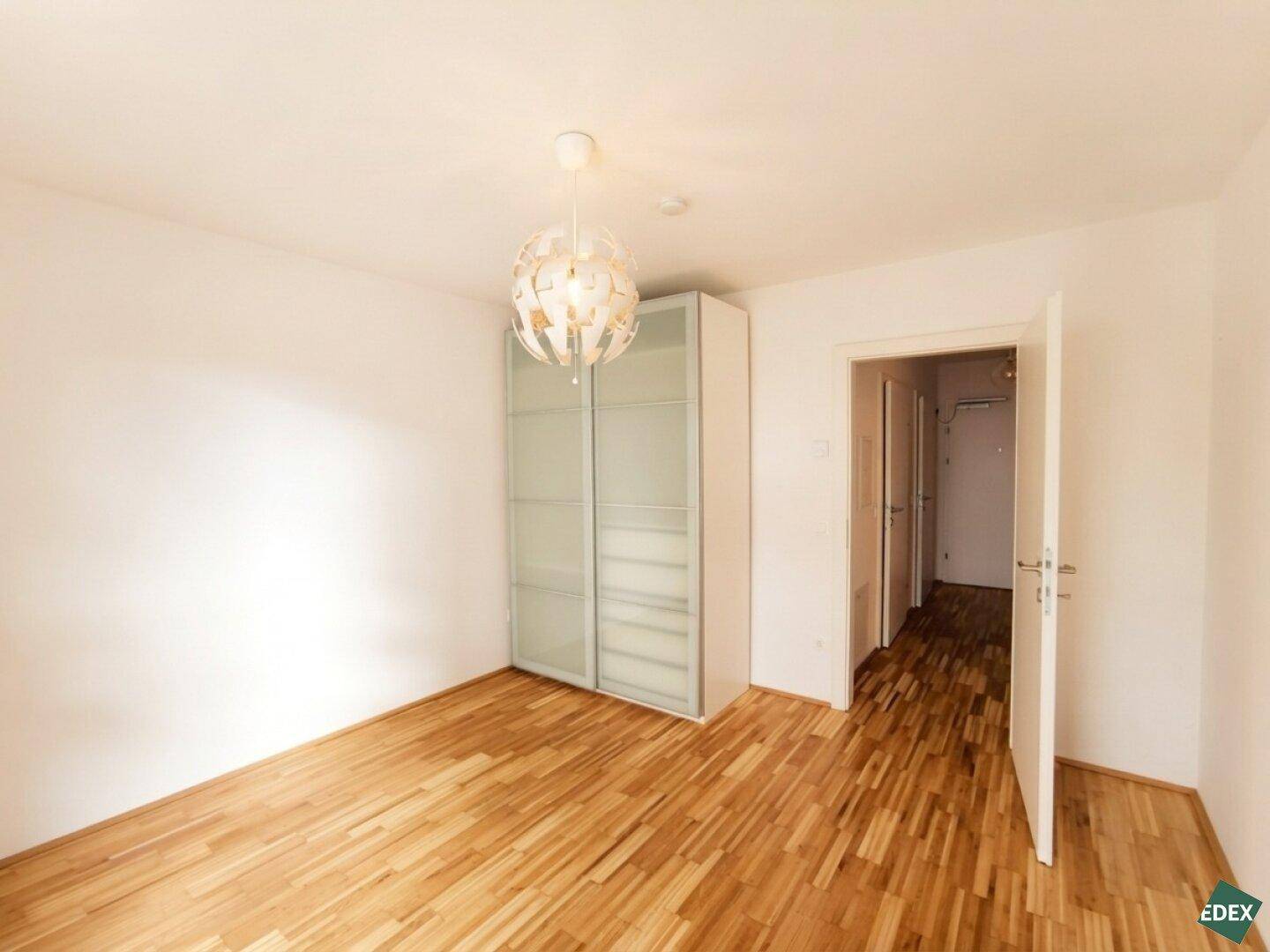 Geräumiges Schlafzimmer mit Parkettboden und einem praktischen Kleiderschrank.