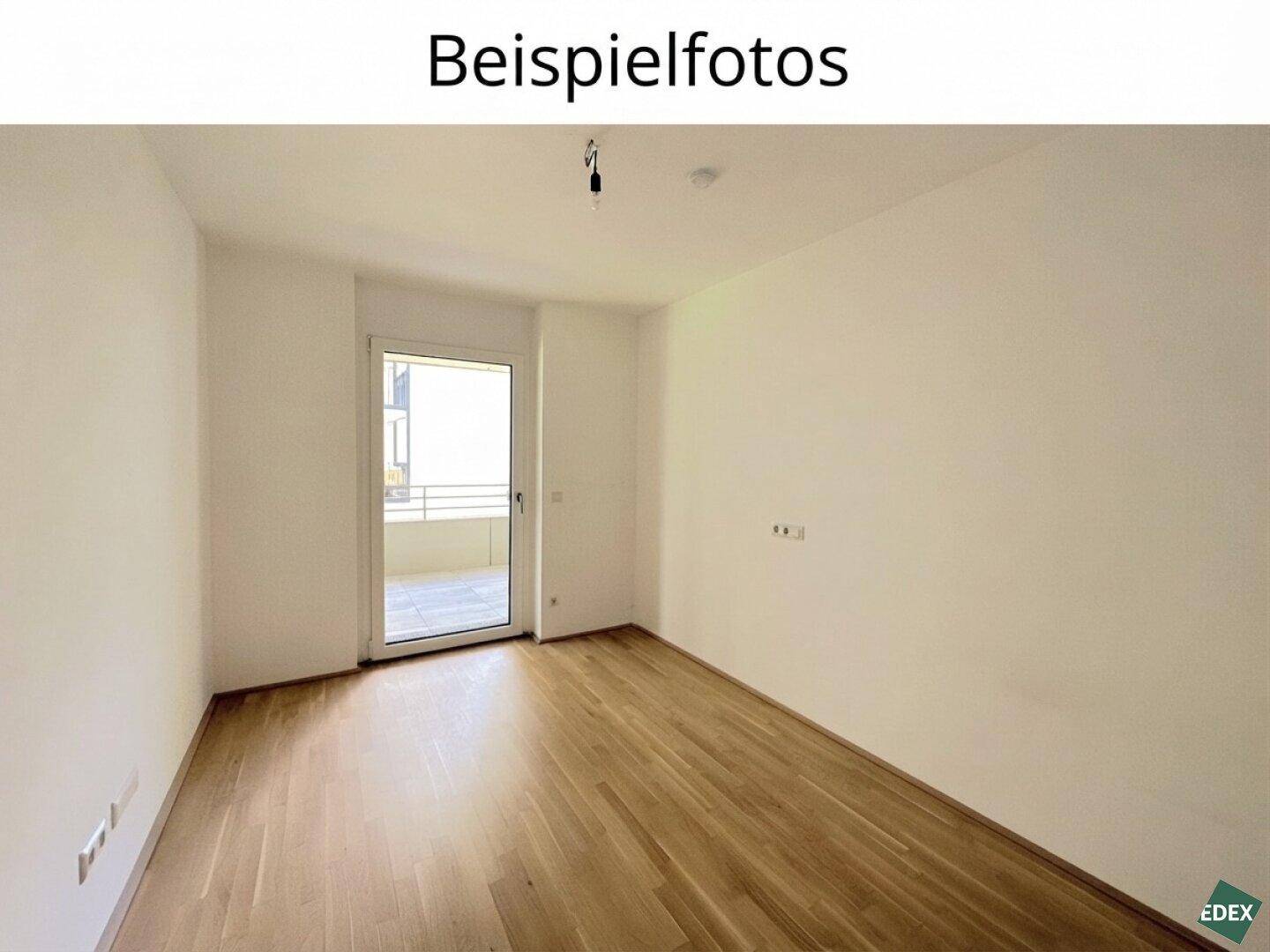 Helles, leeres Zimmer mit Holzboden und direktem Zugang zu einem kleinen Balkon.