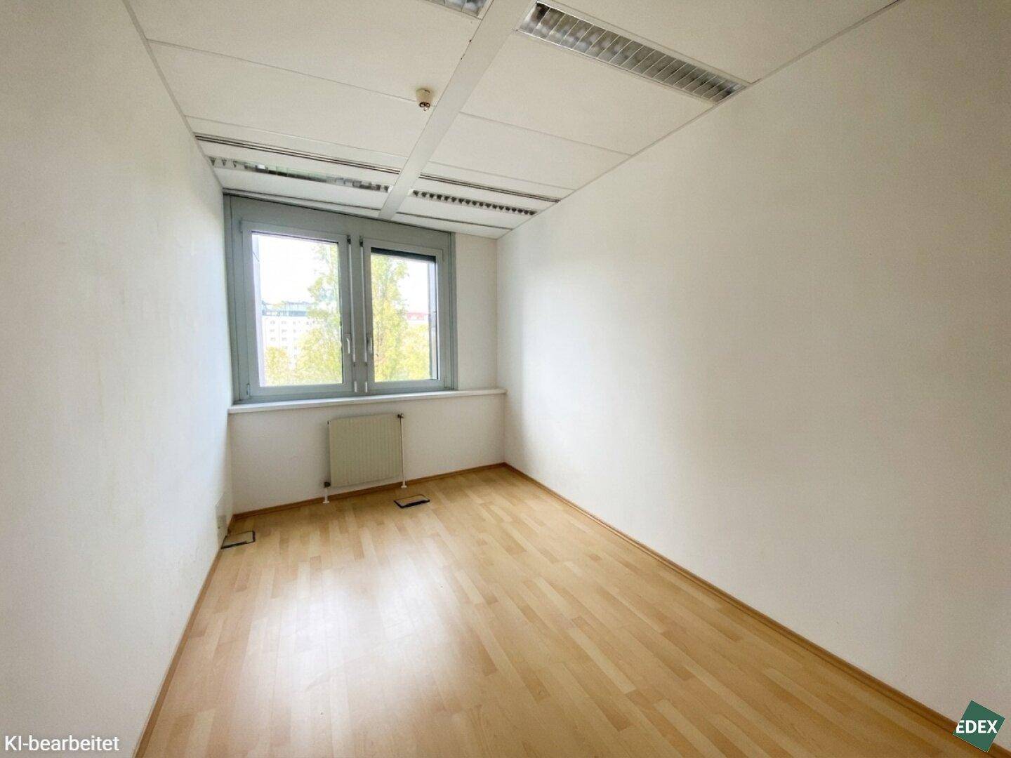 Kleineres, helles Büro mit Holzfußboden, weißen Wänden und zwei Fenstern für natürliche Belichtung.