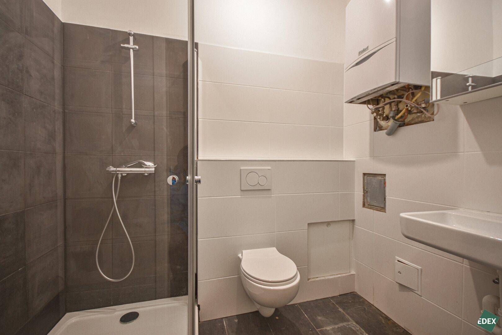 Modernes Badezimmer mit Duschkabine, wandhängendem WC und Gastherme.