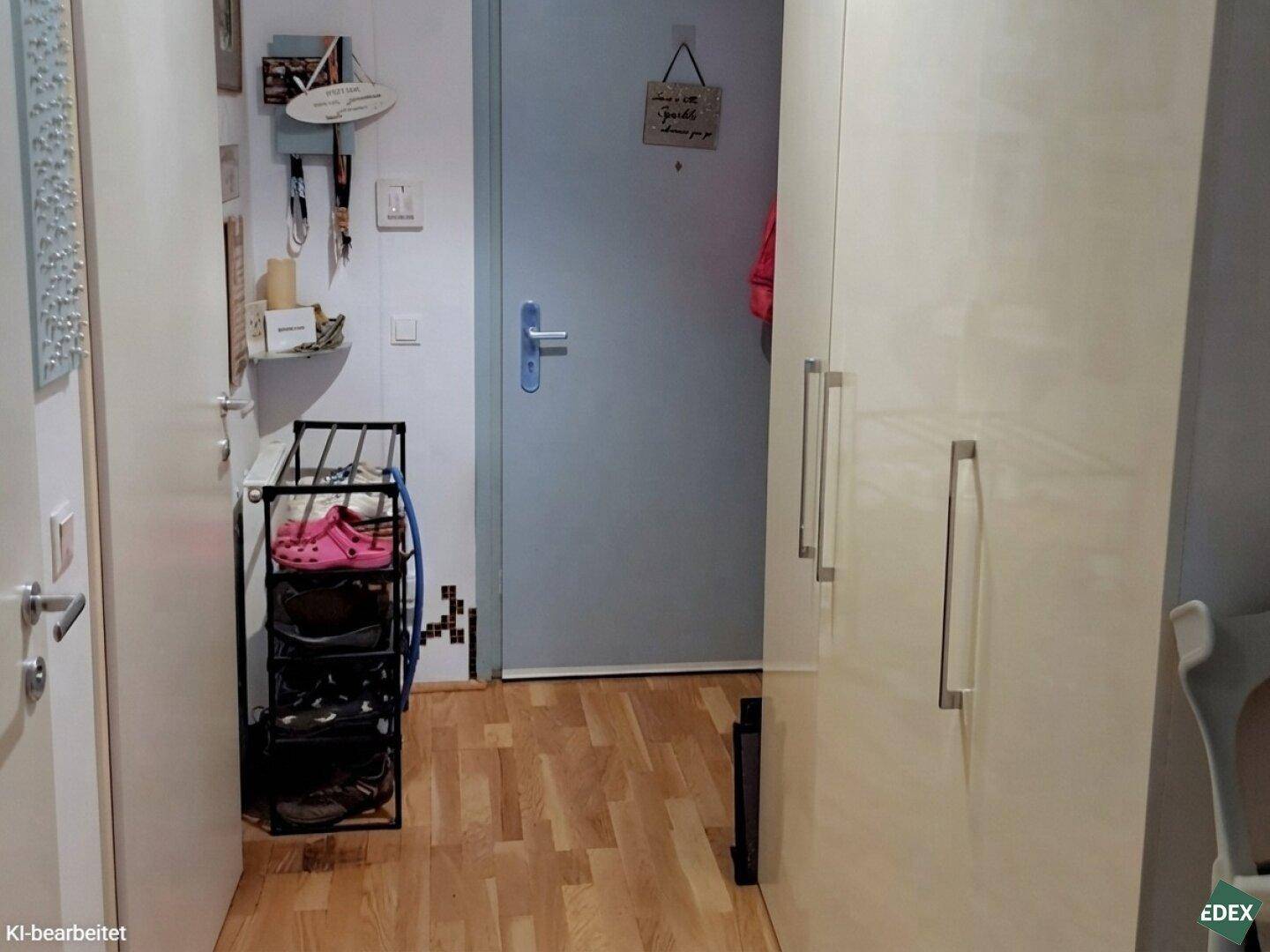 Eingangsbereich mit Garderobe, Schuhregal und heller Holzboden.