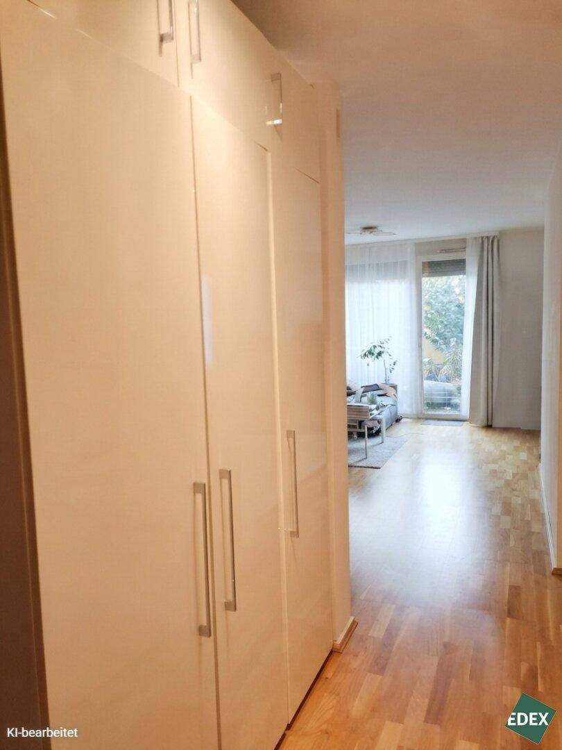Heller Flur mit Einbauschränken und Blick in den Wohnbereich mit Zugang zur Terrasse.