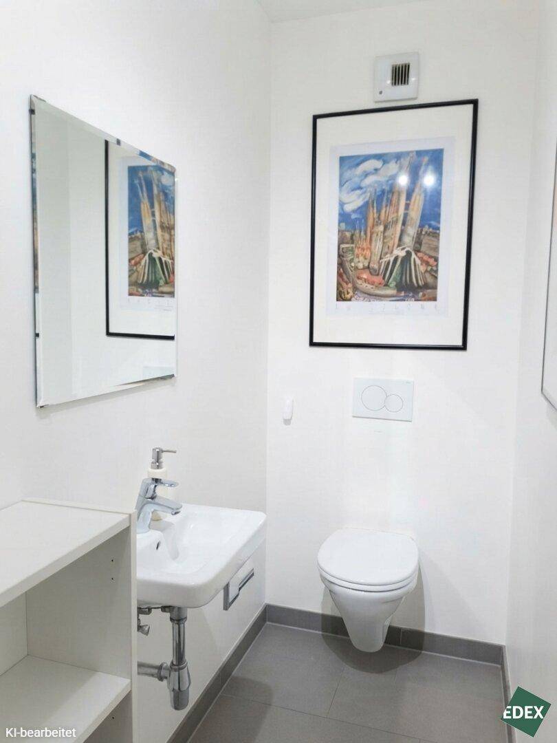 Separates WC mit wandhängender Toilette und kleinem Waschbecken.