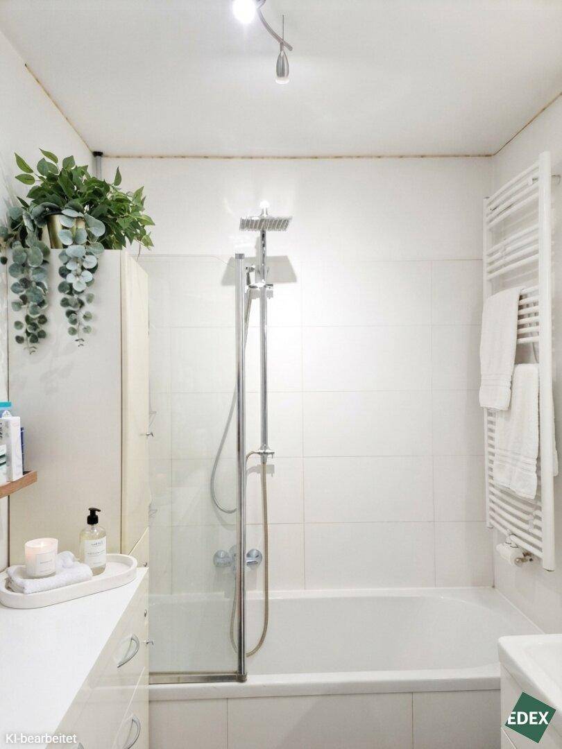 Modernes Badezimmer mit Badewanne, Duschfunktion und beheiztem Handtuchhalter.