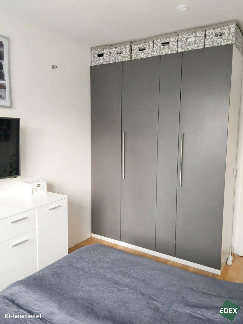 Schlafzimmer mit großem grauen Kleiderschrank und hellem Holzboden.