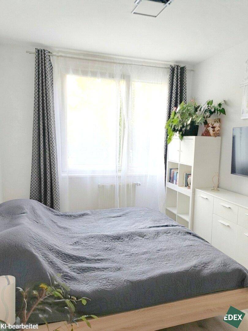 Helles Schlafzimmer mit großem Bett, Fenster und schlichten Möbeln.