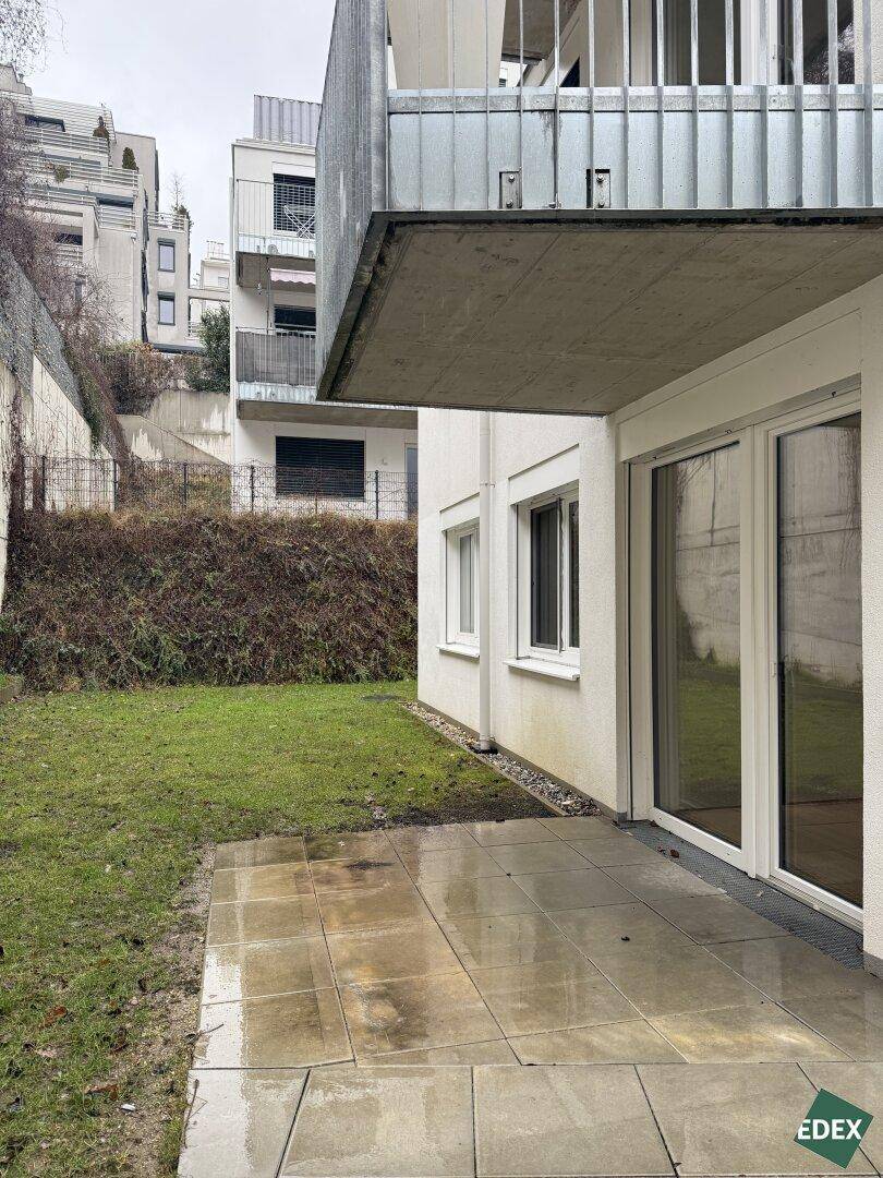 Terrasse mit Fliesenboden und angrenzender Rasenfläche im Erdgeschoss.