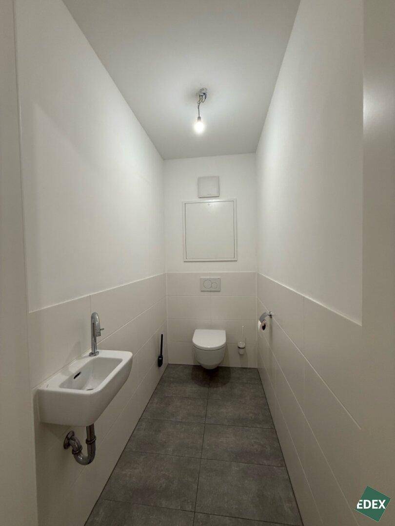 Separates Gäste-WC mit wandhängendem WC und kleinem Waschbecken.